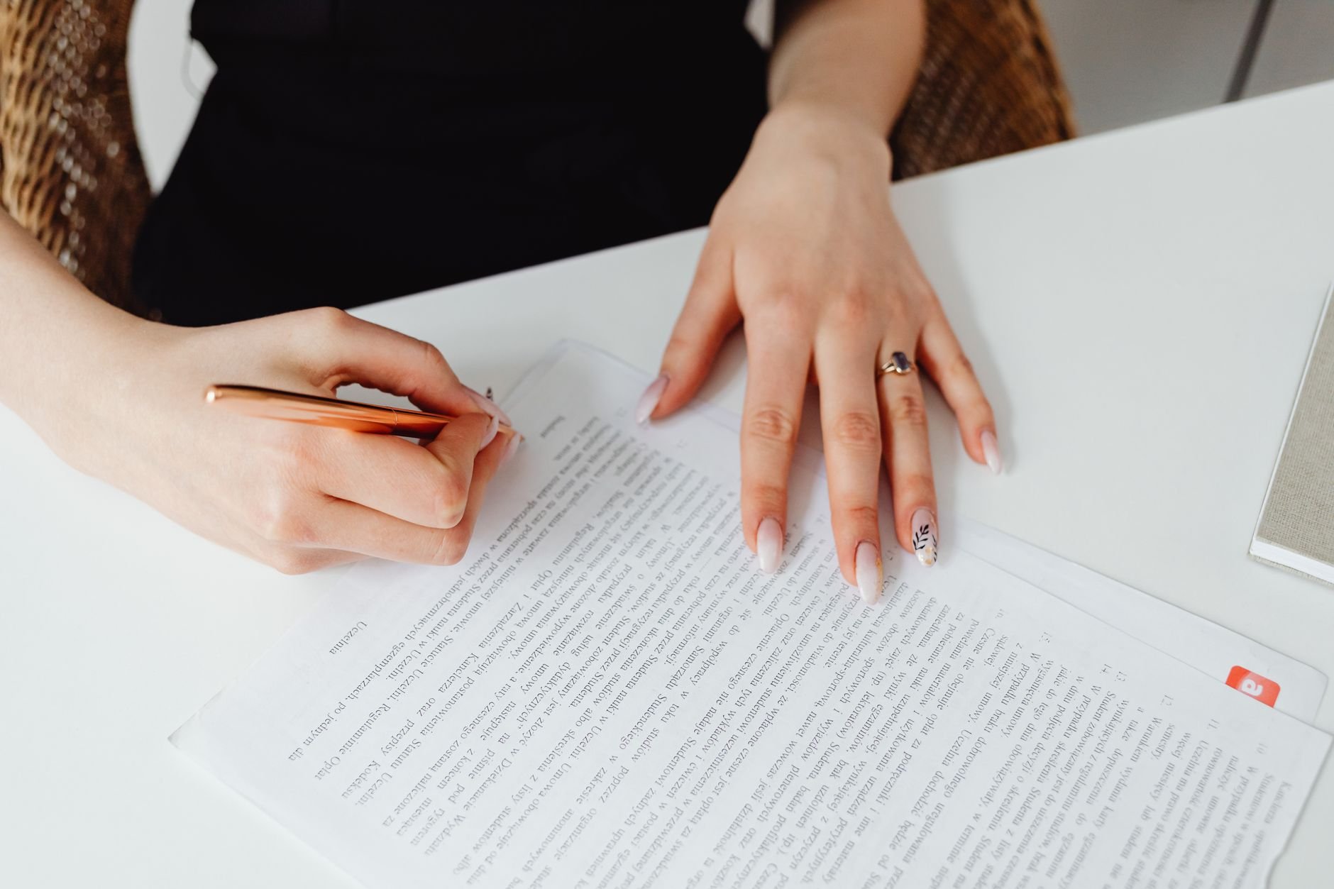 A person carefully signing a document on a desk — administrative tasks handled with attention.